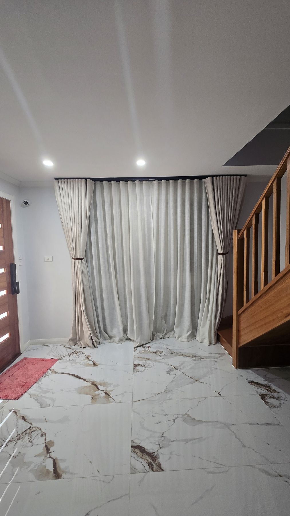 After — the entry and staircase on reveal night, curtains hung and marble laid