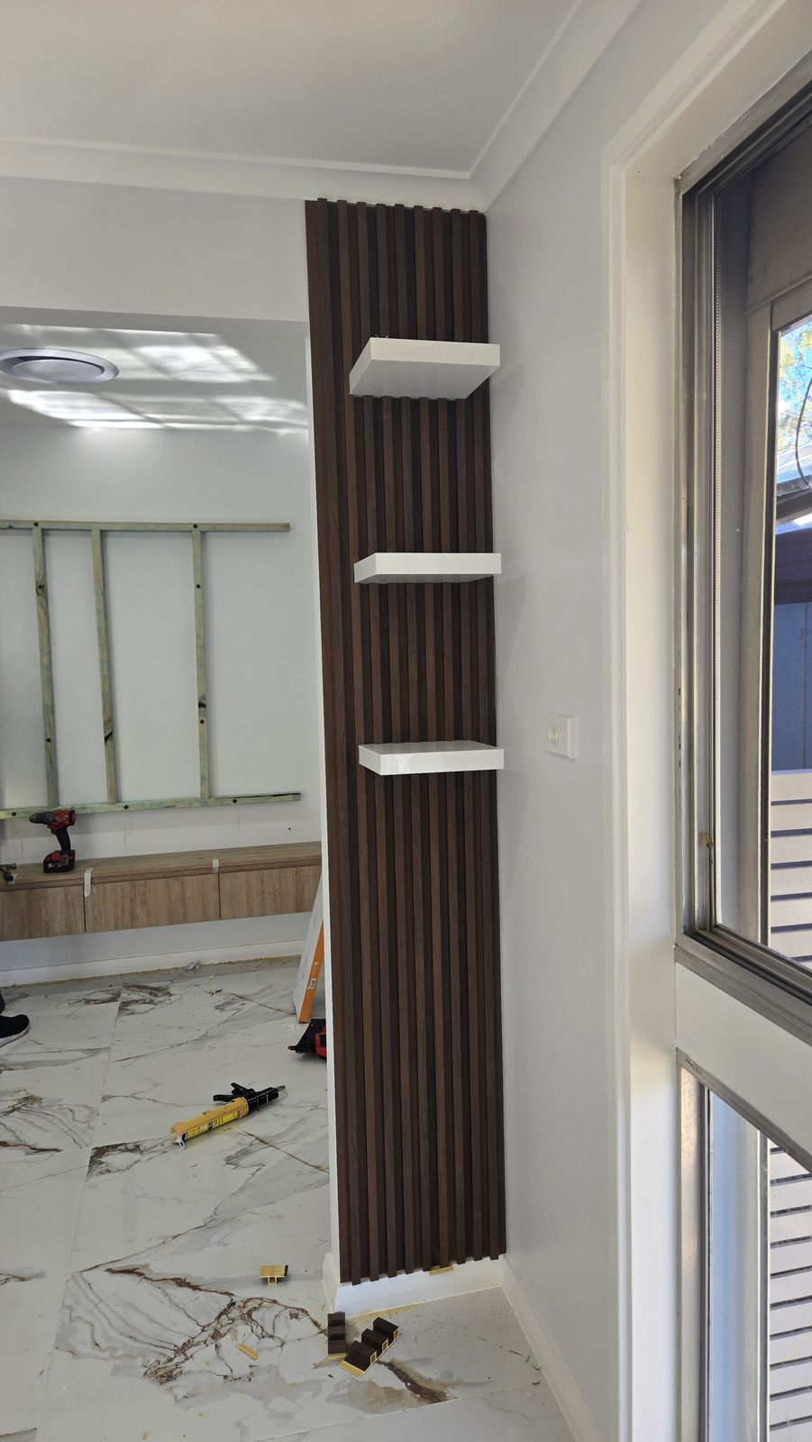Walnut slat feature wall mid-installation