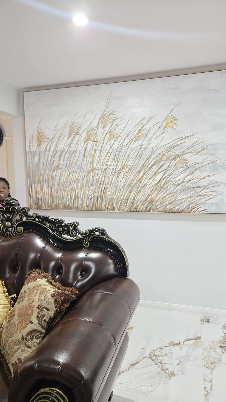 Baroque leather sofa beneath a golden reed artwork